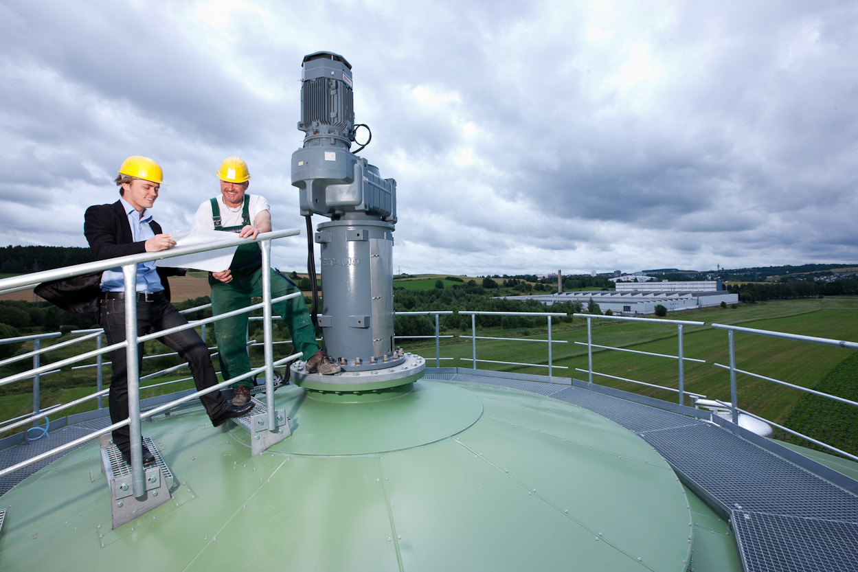 Eine Biogasanlage in Hof. Projektleiter und Mitarbeiter des Projekts stehen auf dem Fermenter, wo der biologische Prozess startet.